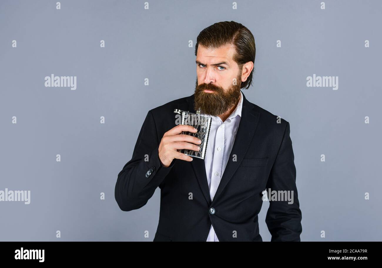 Always with me. Flat metal bottle for alcohol. man with elegant look. bearded hipster in suit hold metal flask for alcohol. Alcohol drink concept. Have alcohol drink with you. copy space. Stock Photo