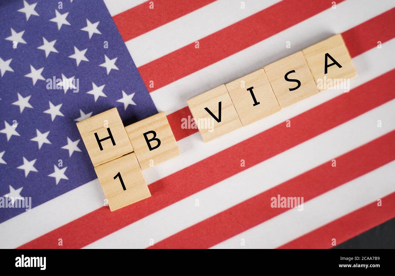 Concept of H1b Visa for foreign workers showing wooden letters with US or United states flag as background Stock Photo