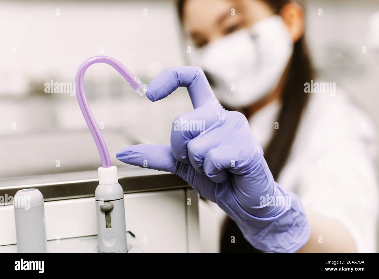 Dental treatment, healthcare and dentistry concept. The woman's hand shows the heart together with the saliva ejector. Stock Photo