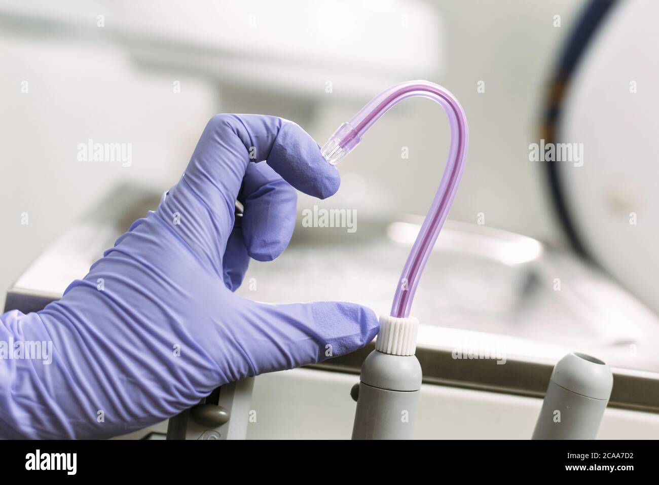 Hand in Blue latex glove and saliva ejector symbolize love in dentistry