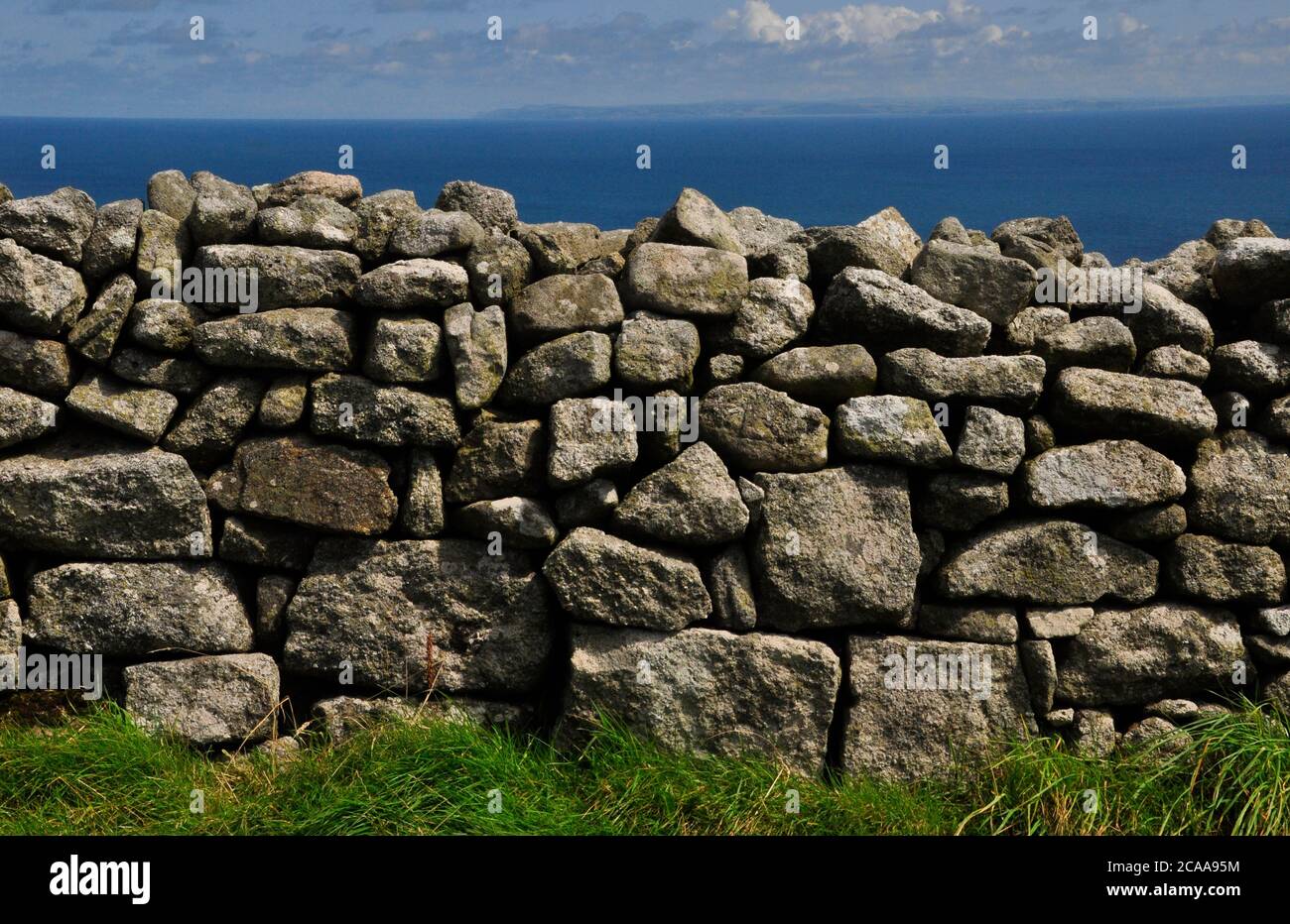 Random laid granite stone wall on the island of Lundy in the Bristol channel off the north coast of Devon which is visible on the horizon. Stock Photo