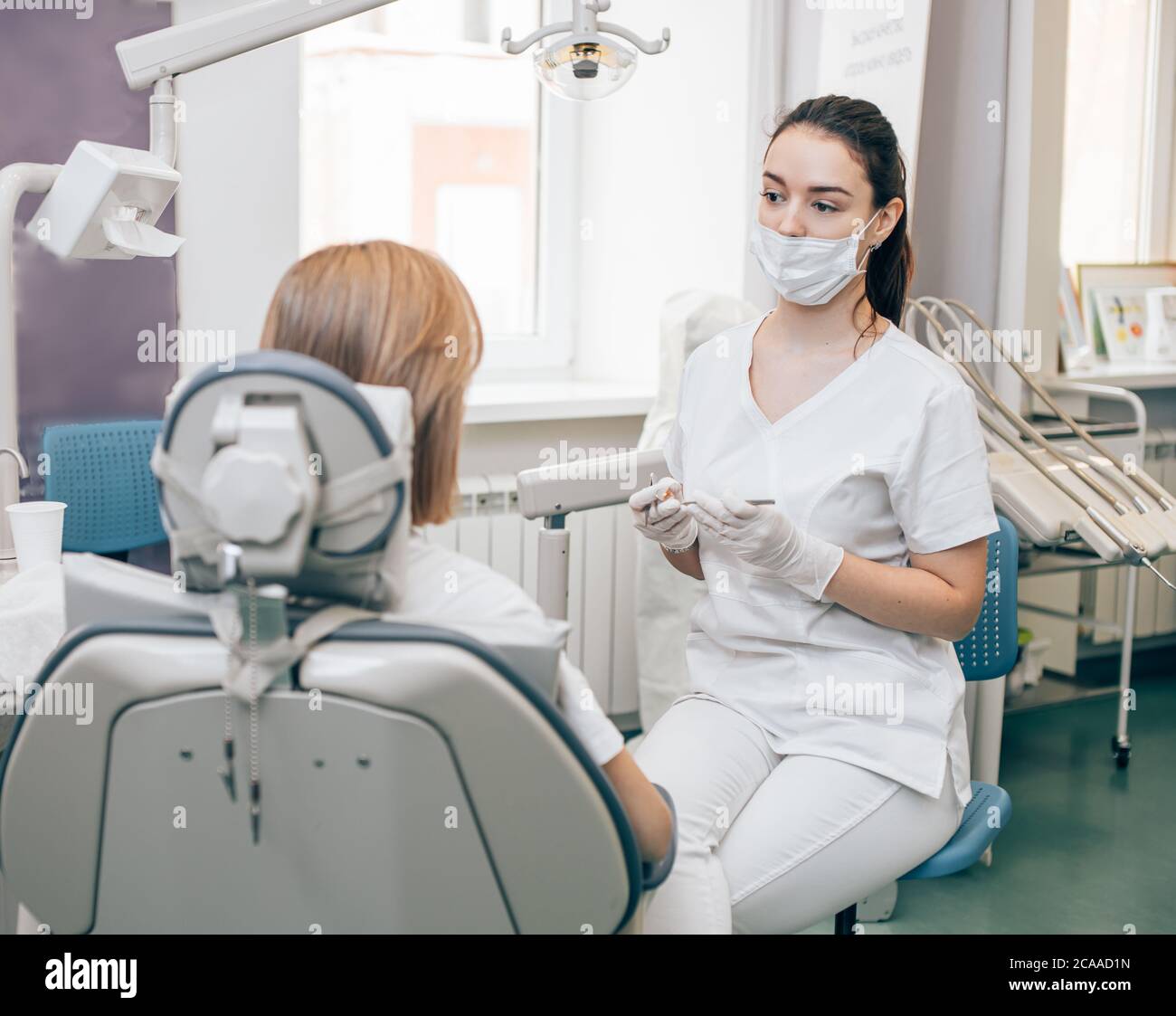 careful dentist woman in white doctor's uniform treating teeth