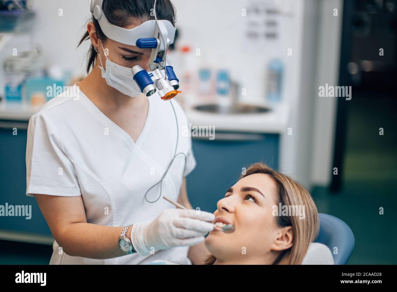 careful dentist woman in white doctor's uniform treating teeth