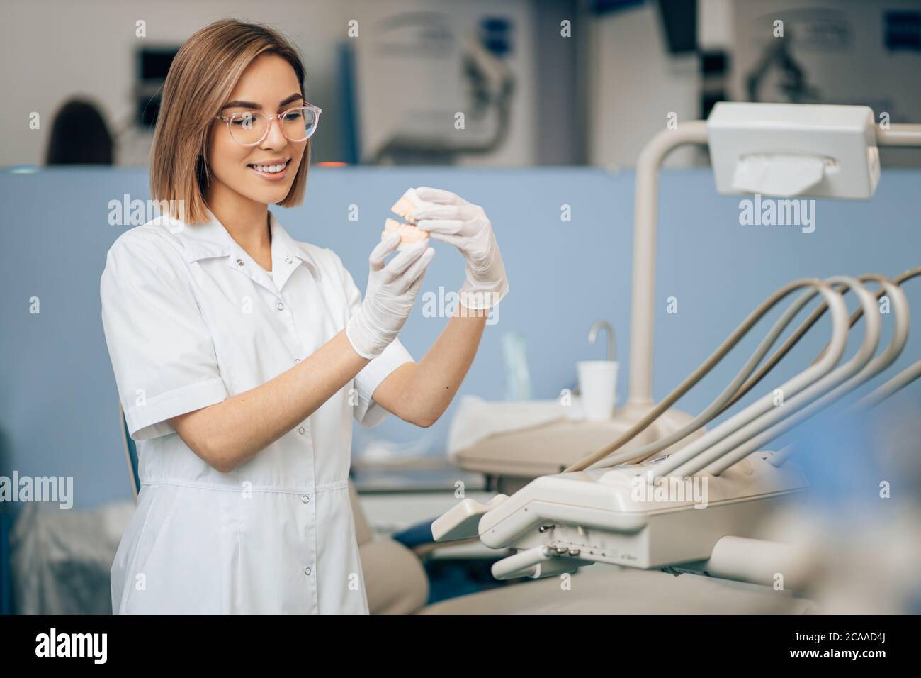 portrait of dental specialist at work, wearing white doctor's uniform, using medical instruments and equipment. Healthcare concept Stock Photo