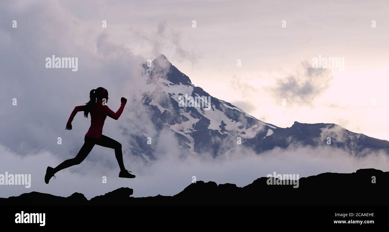 Running woman athlete trail running in mountain summit background. Female runner on run training outdoors living active fit lifestyle. Silhouette at Stock Photo