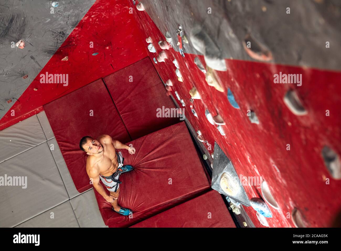 Top view of shortless athletic man bouldering at indoor climbing centre