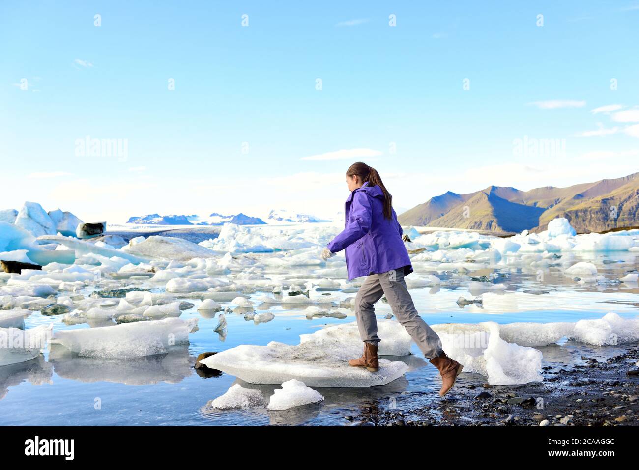 Iceland travel tourist walking on ice looking at view of nature landscape Jokulsarlon glacial lagoon on Iceland. Woman hiking by tourist destination Stock Photo