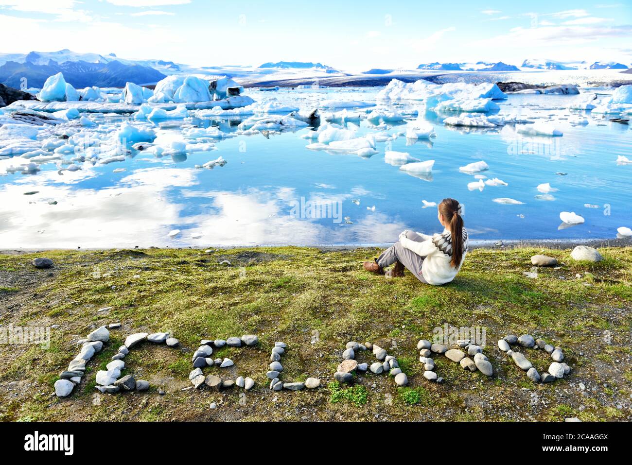 Iceland nature landscape Jokulsarlon glacial lagoon - ICELAND text written with rocks. Woman enjoying view visiting tourist destination landmark Stock Photo