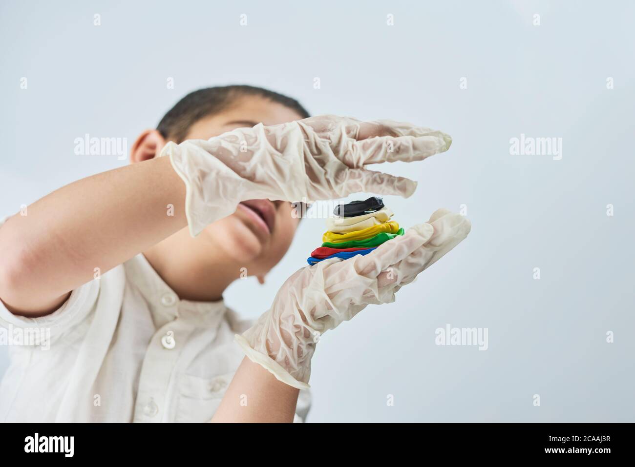 Close-up portrait of mixed raced child in glasses and gloves experimenting with slime Stock Photo