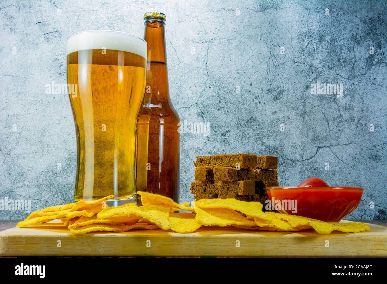 Lager beer and snacks on stone table. Cracker, chips side view Stock Photo