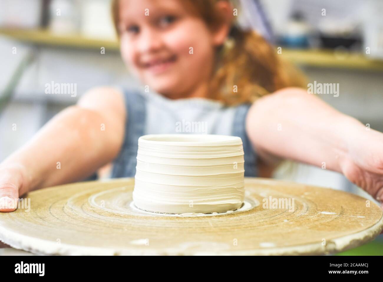 Child holds up a bowl made during ceramic pottery making class Stock