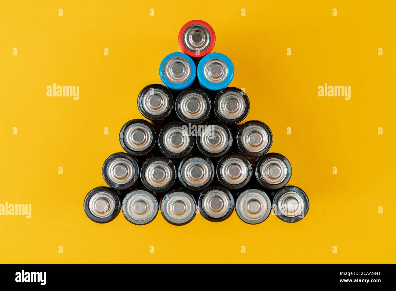 Top view of used batteries arranged in a triangle shape isolated on a yellow background Stock Photo