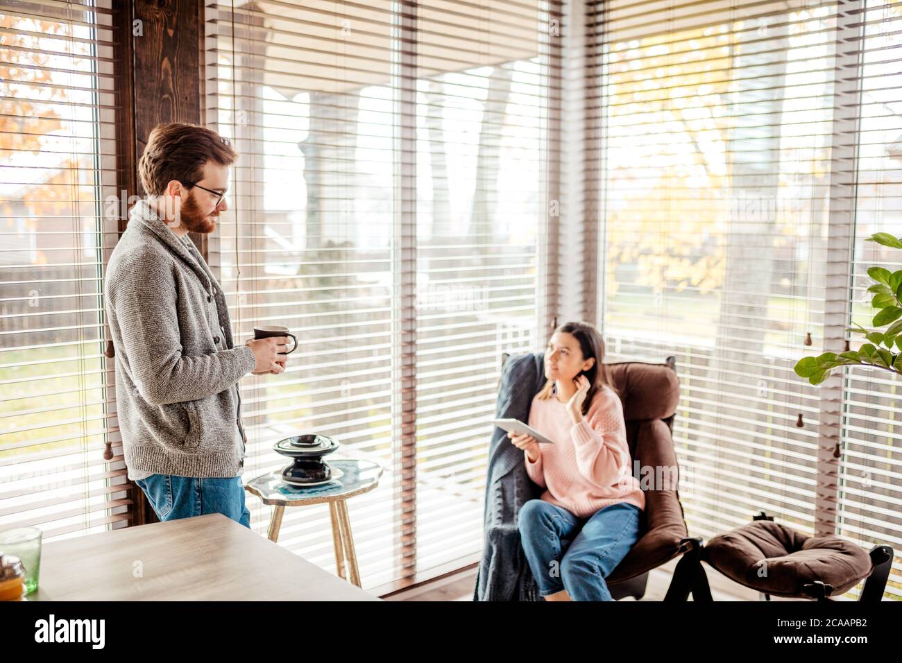 Attractive young couple discussing purchase of a new house in a well-lit modern kitchen while they are talking and drinking coffee Stock Photo