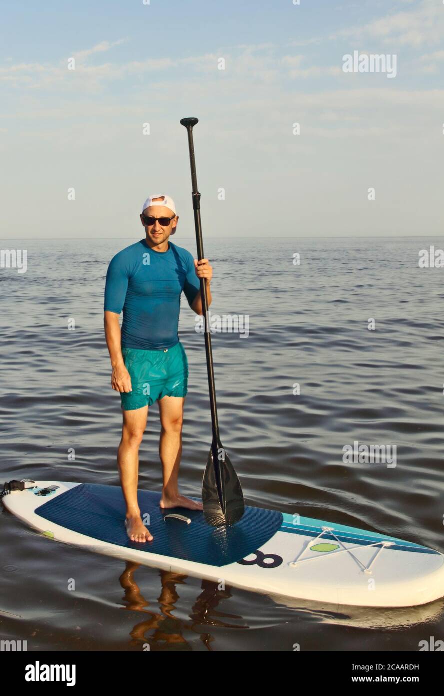 SAP Board surfing. Man is training on a SUP board in the summer sea at  sunny day Stock Photo - Alamy