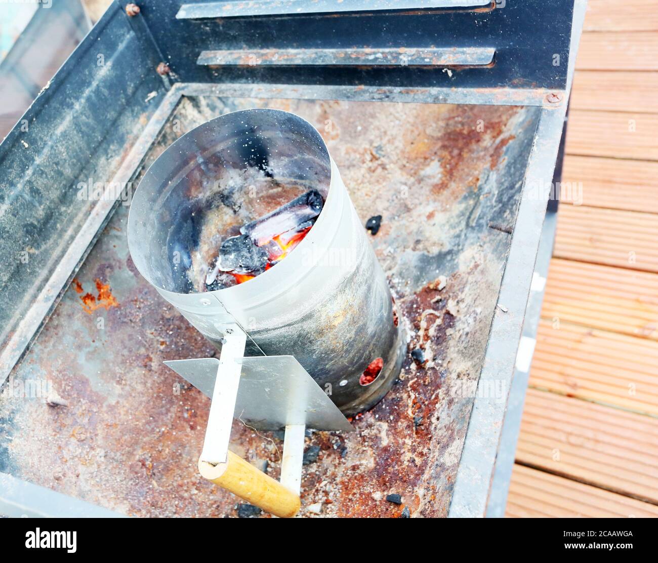 bbq chimney starter with burning charcoal and ember ready to pour into bbq Stock Photo