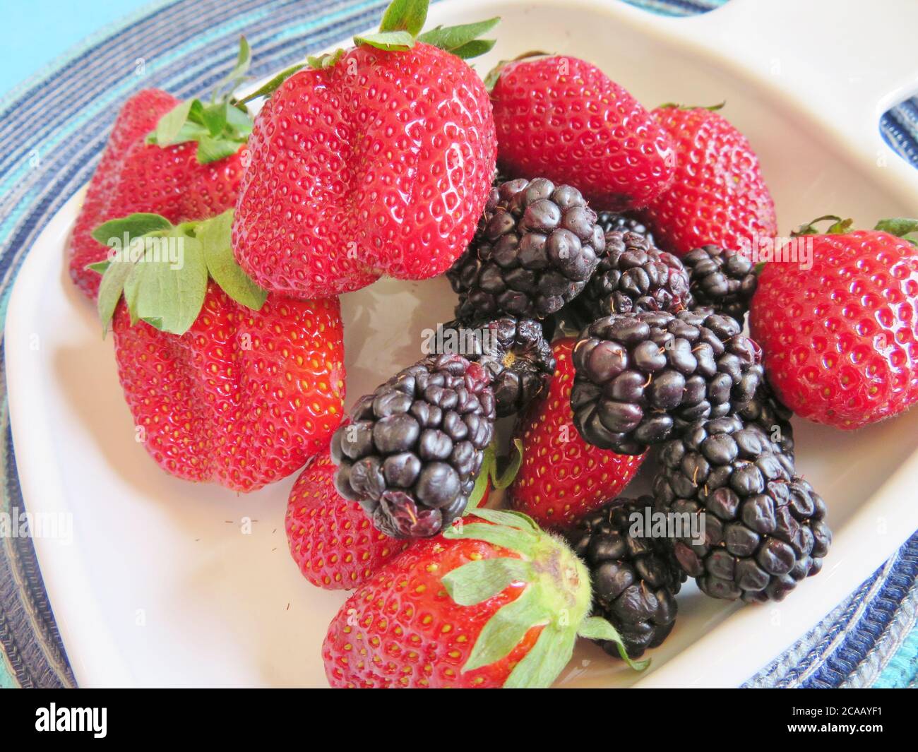 An assortment of berries; fresh, ripe strawberries and blackberries Stock Photo