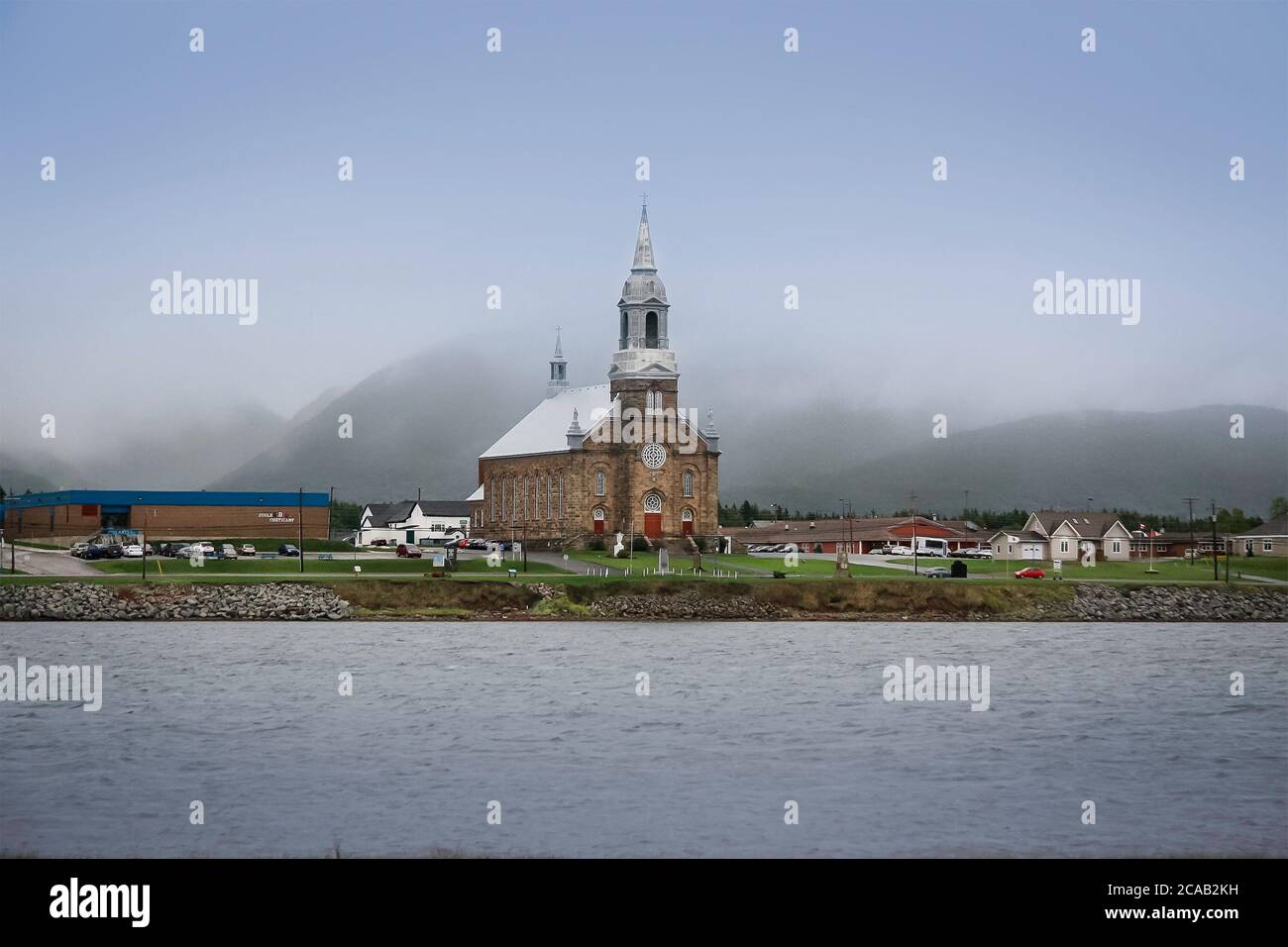 tranquil scene of an Acadian village abroad the sea in Cheticamp with church and small houses in  rural country of Nova Scotia, Canada Stock Photo