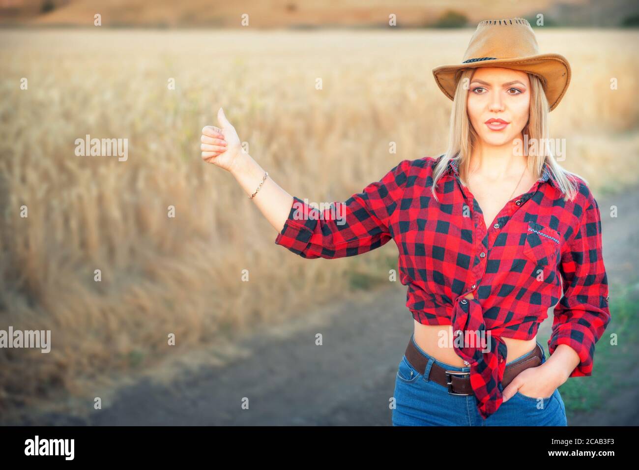Young beautiful woman wearing cowboy hat as a hitchhiker Stock Photo