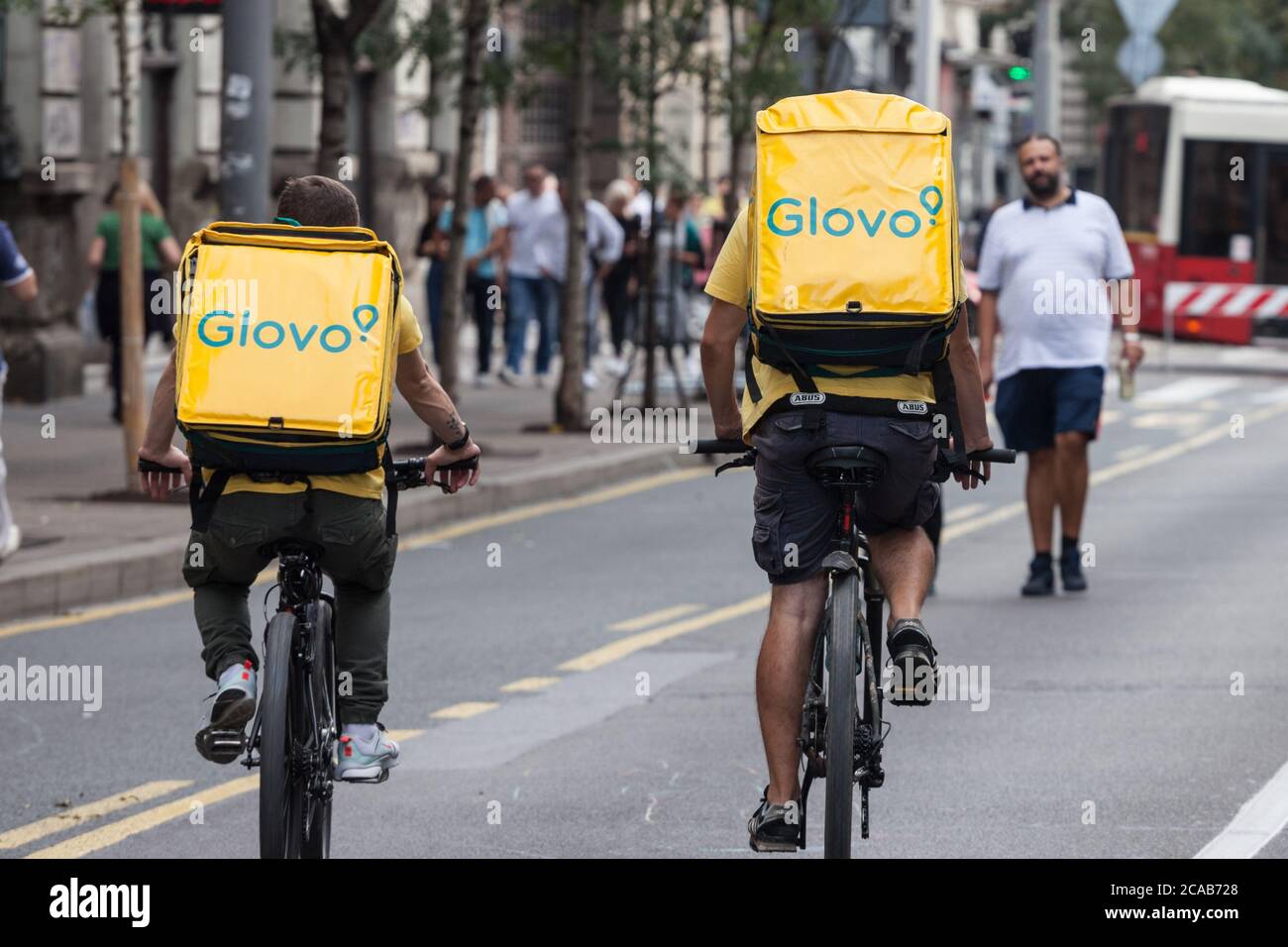 BELGRADE, SERBIA - SEPTEMBER 28, 2019: Glovo logo on the bag of two delivery men on their bicycles in belgrade. Glovo is a Spanish Food delivery app s Stock Photo