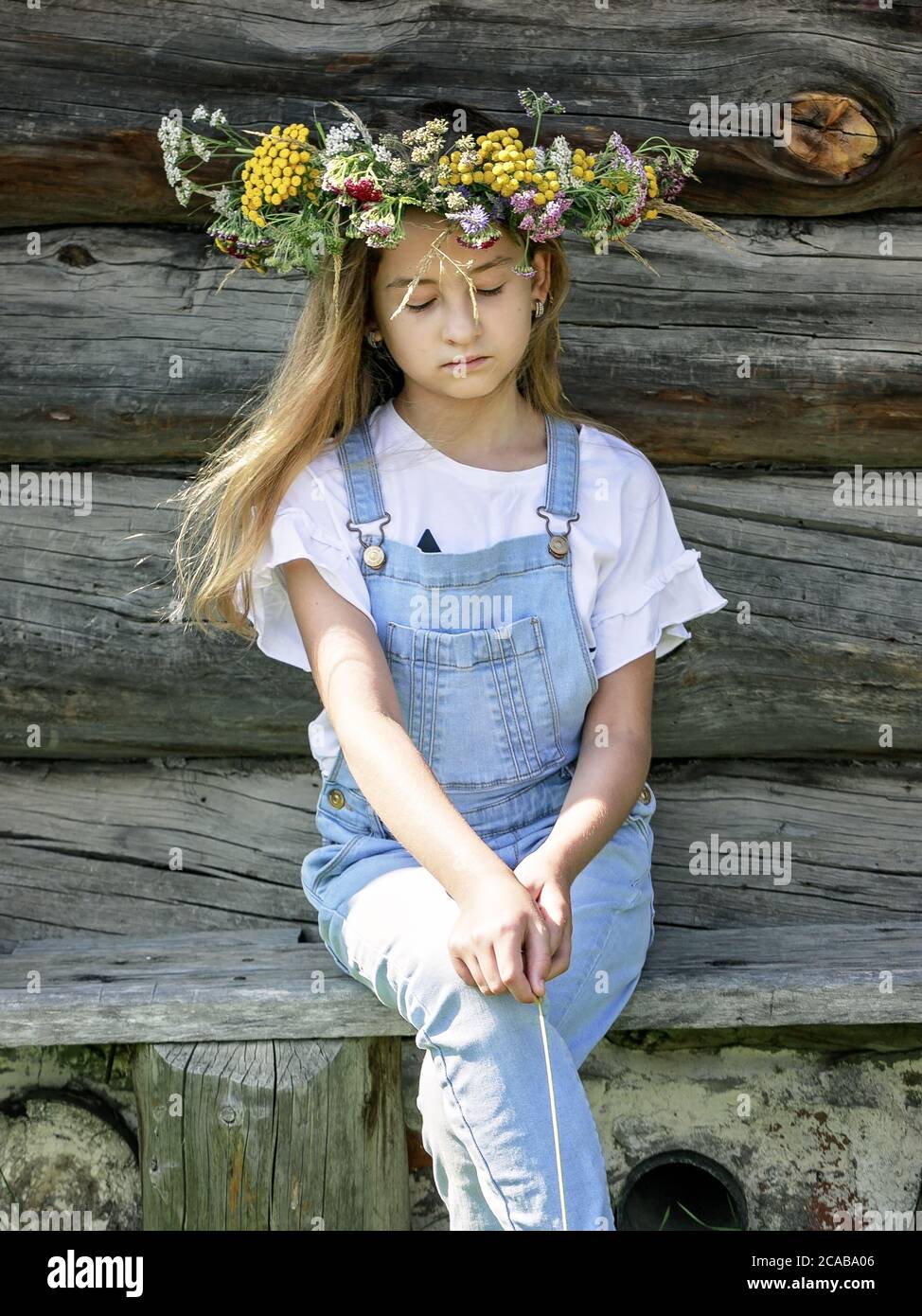 Summer portrait of a sad girl. Cute teenage girl in flower wreath. Vertical shot Stock Photo