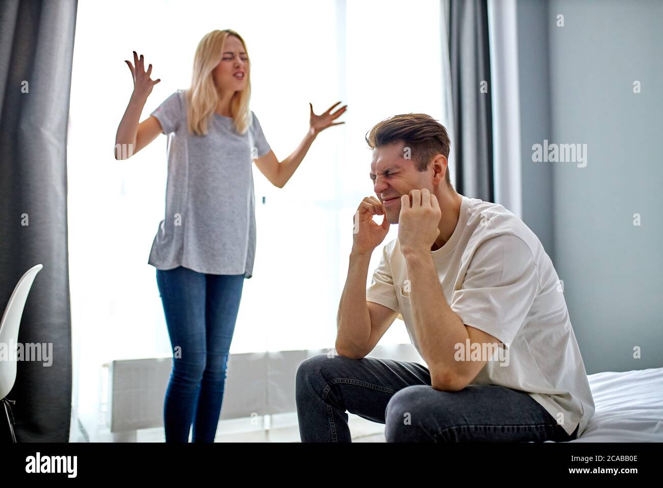 young caucasian man 20-25 years old don't want listen to screaming wife, they argue at home, in domestic clothes, unhealthy relationships, problems Stock Photo