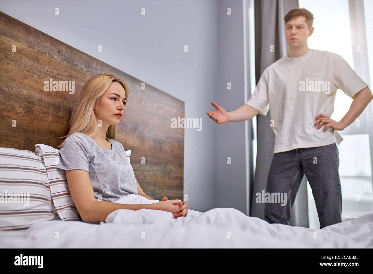 how much one can sit offended,do the housework dissatisfied man want her lazy wife to do housework, offended woman sits on bed Stock Photo