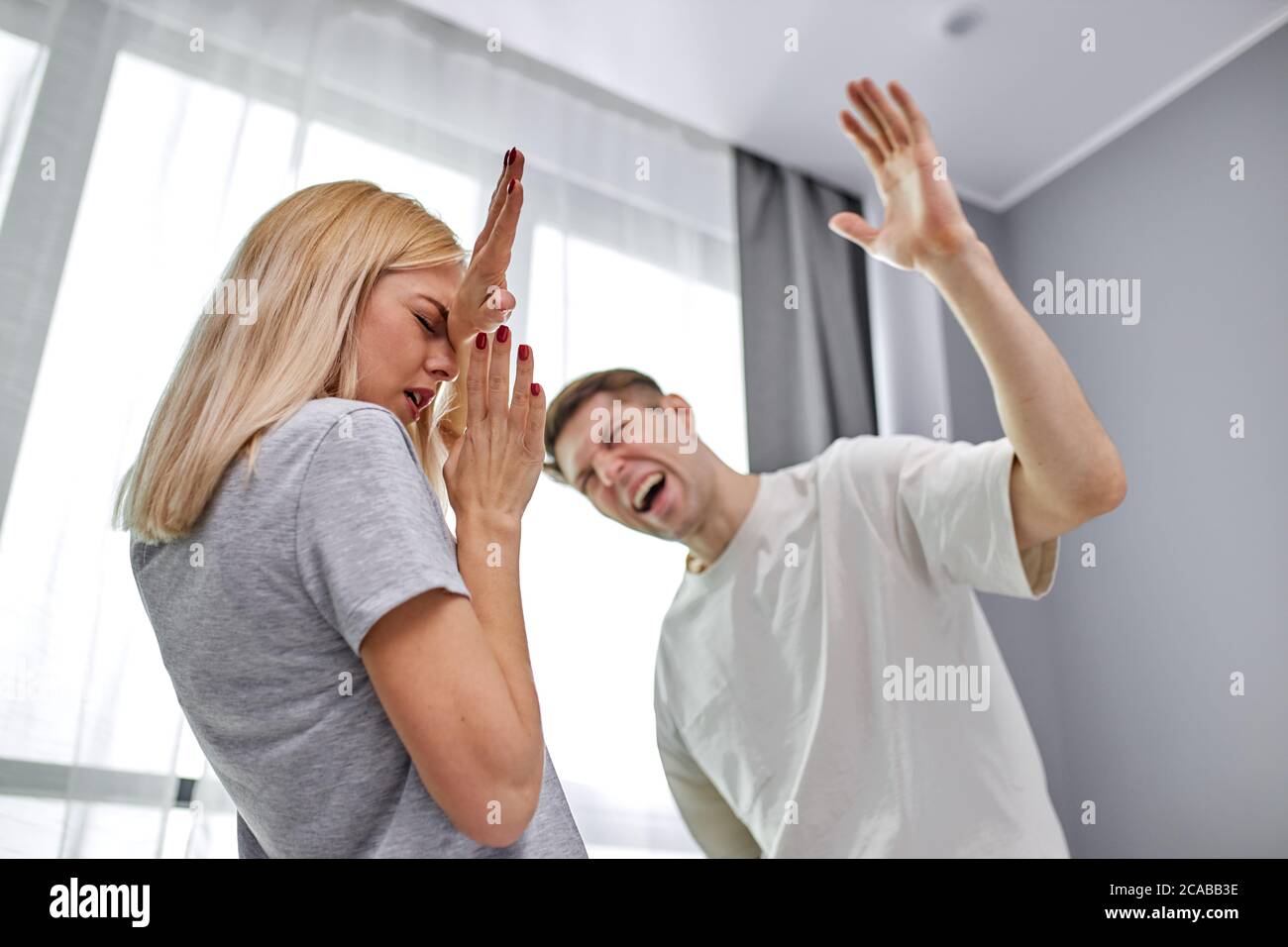 domestic violence, man raises his hand to wife, going to beat and humiliate her at home, woman afraid of him. abusive relationships concept Stock Photo