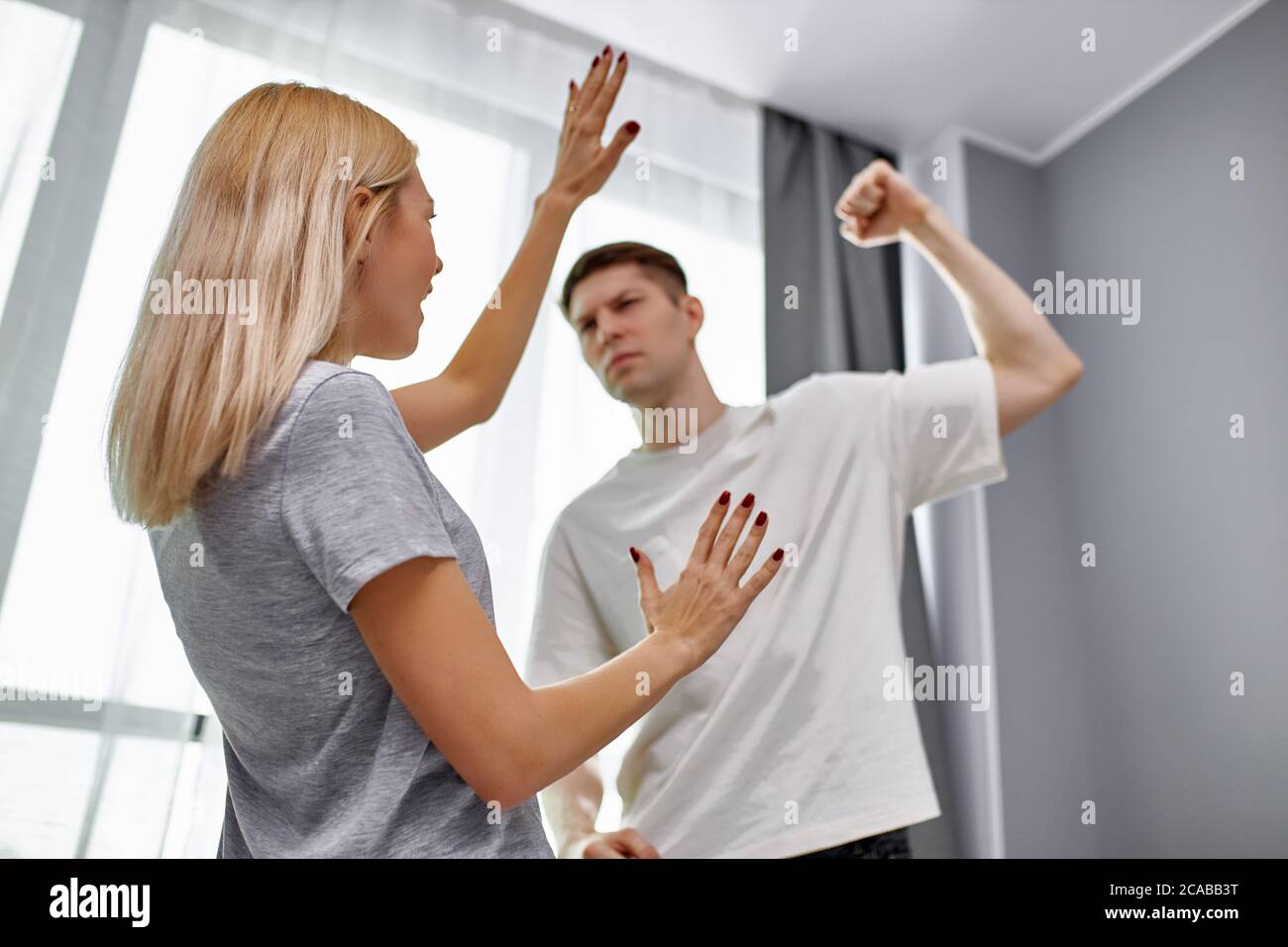 domestic violence, man raises his hand to wife, going to beat and humiliate her at home, woman afraid of him. abusive relationships concept Stock Photo