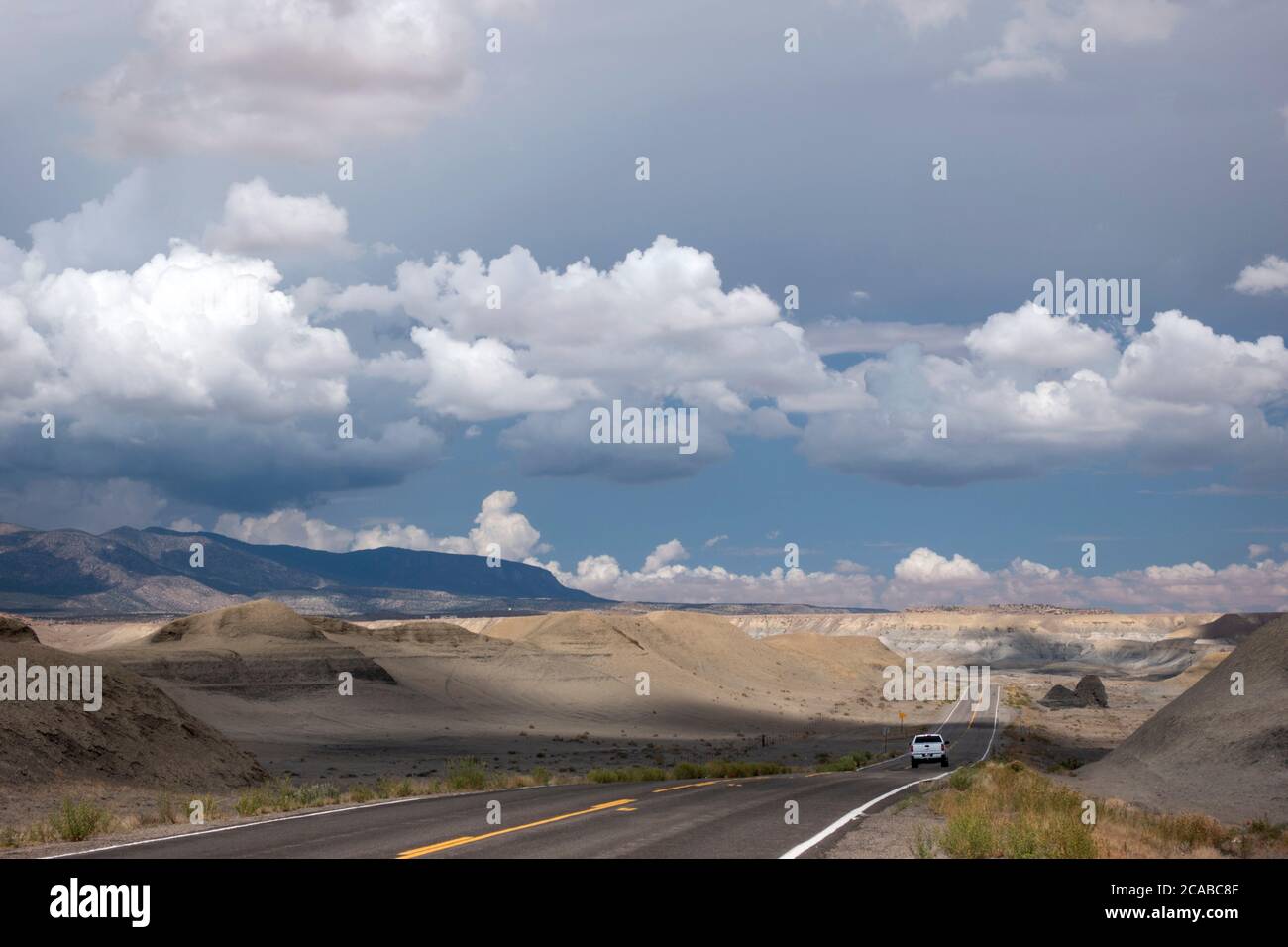 A pickup truck drives along highway 64 near Beclabito, New Mexico towards a thunderstorm in the desert Stock Photo