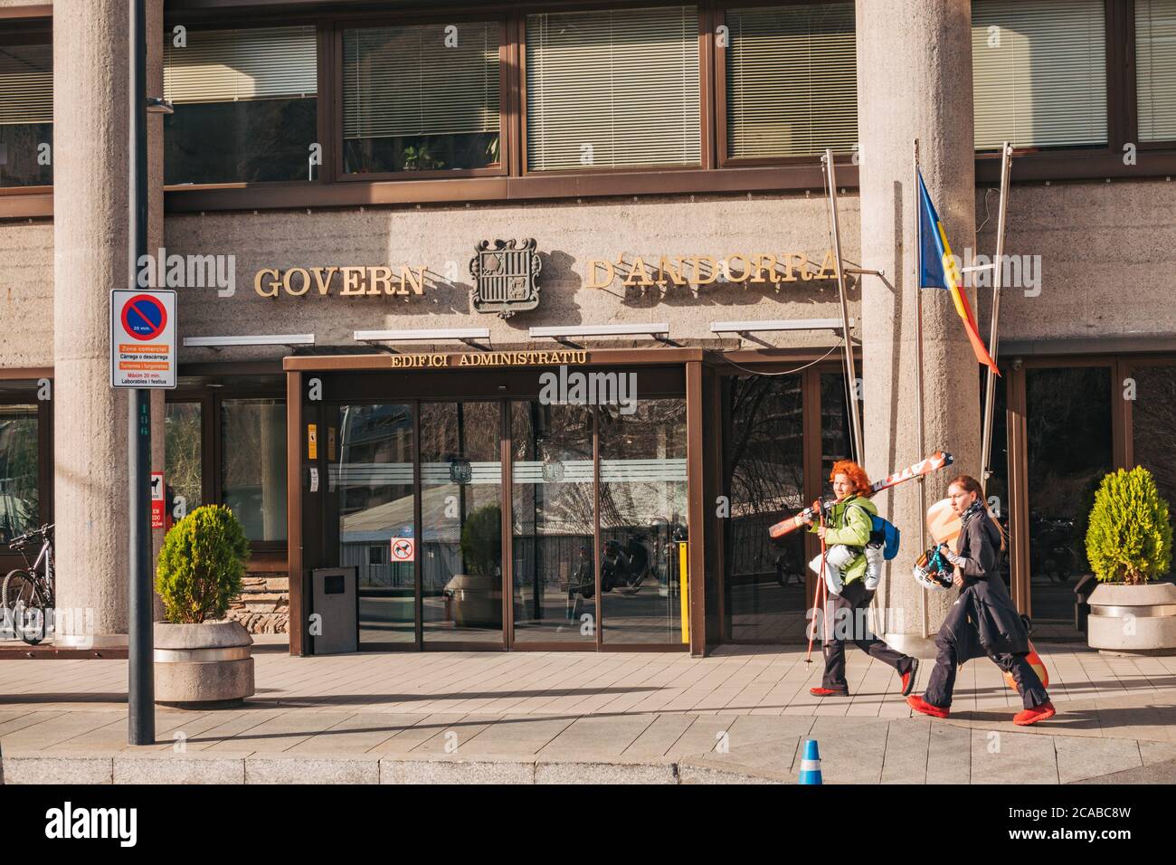 Skiers walk past the Government of Andorra administrative building in the capital city, Andorra la Vella. Locally known as the 'Bunker' Stock Photo