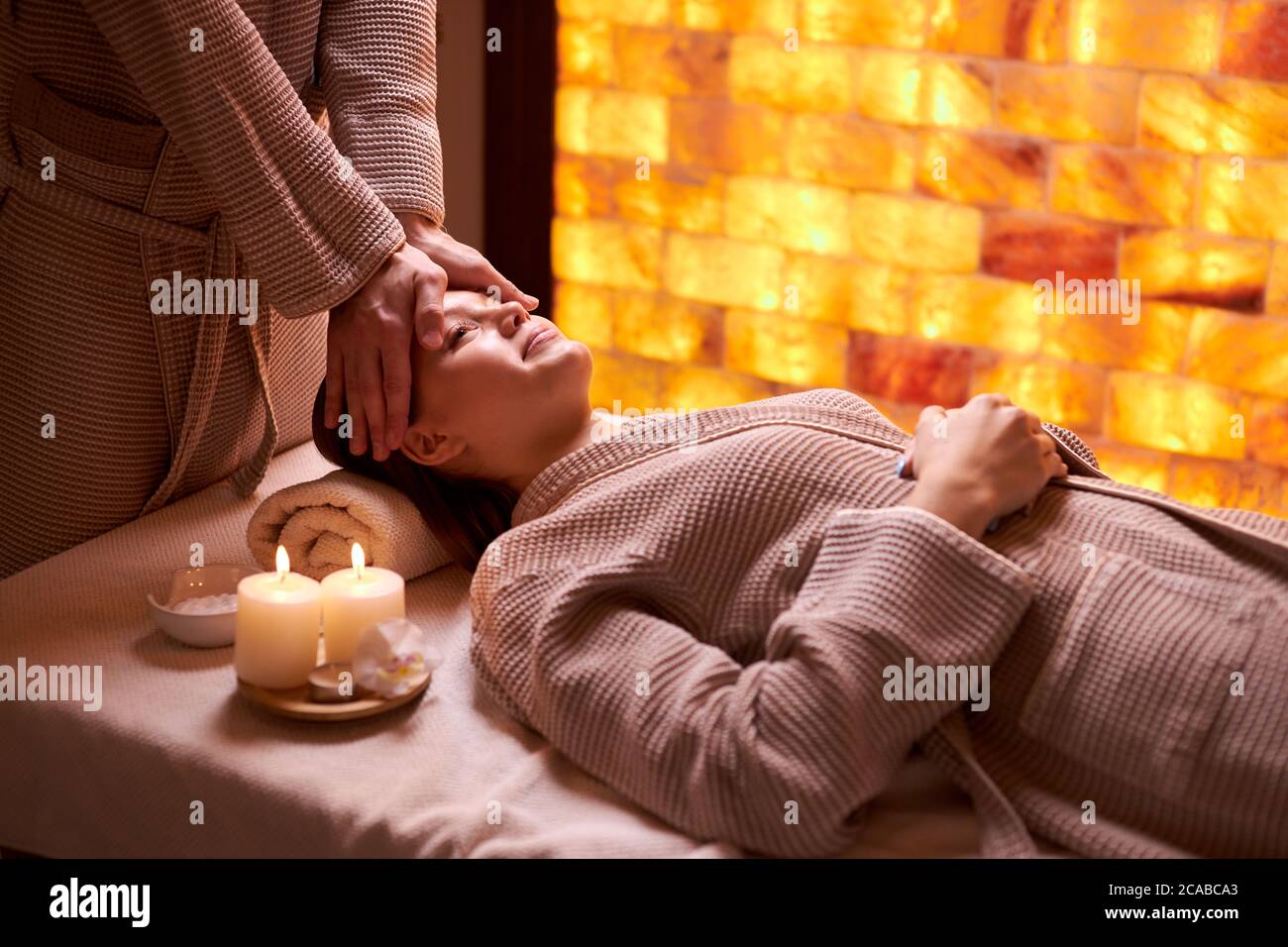 Attractive lady lying down on desk for procedures, getting facial massage in spa salon Stock Photo