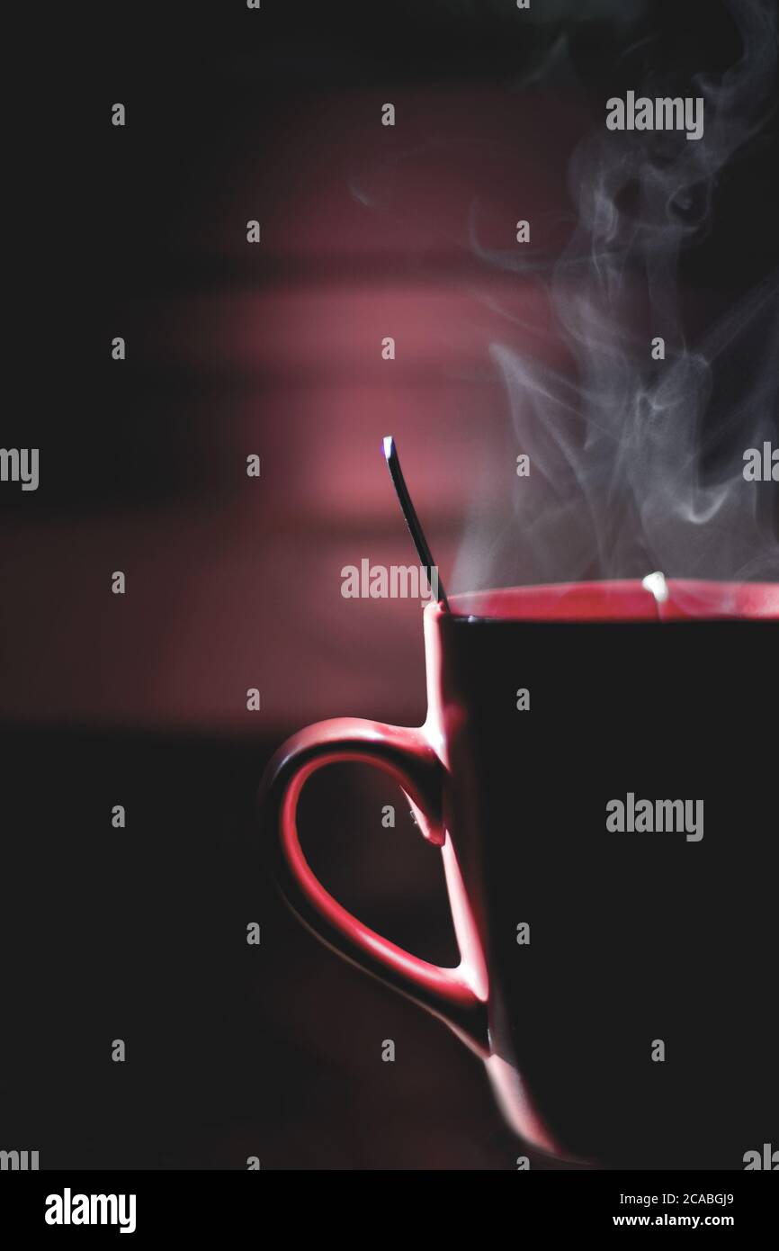 Vertical shot of steam coming out of a red mug with hot drink Stock Photo