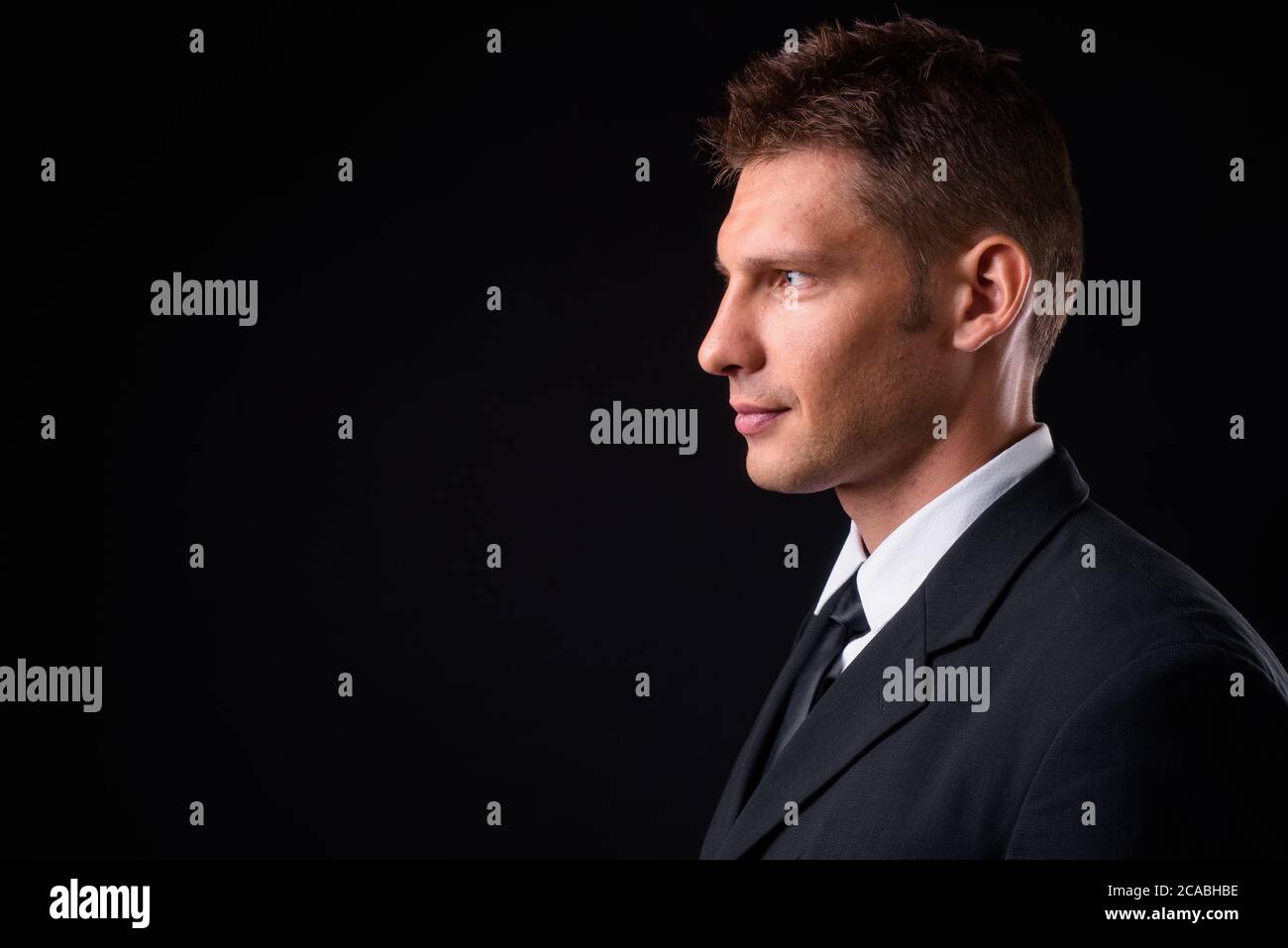 Portrait of businessman in suit against black background Stock Photo ...