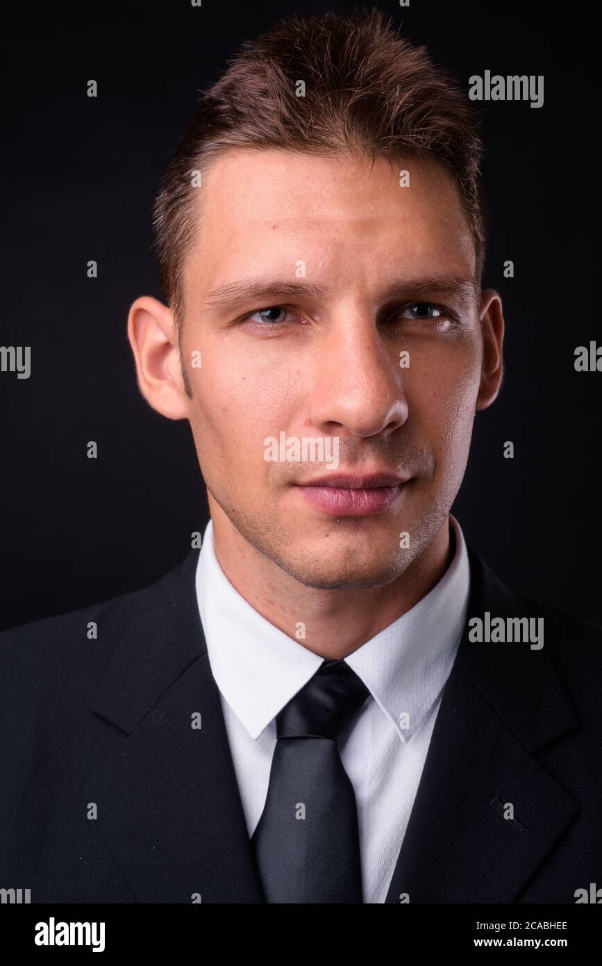 Portrait of businessman in suit against black background Stock Photo ...