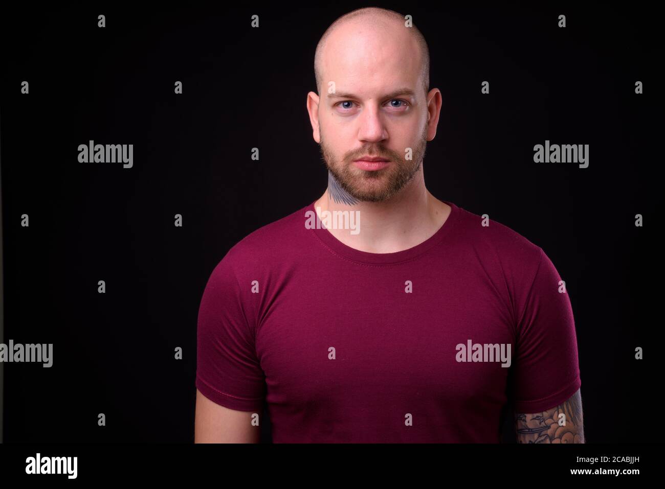 Handsome bald bearded man against black background Stock Photo