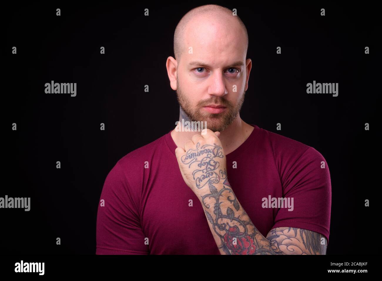 Handsome bald bearded man against black background Stock Photo