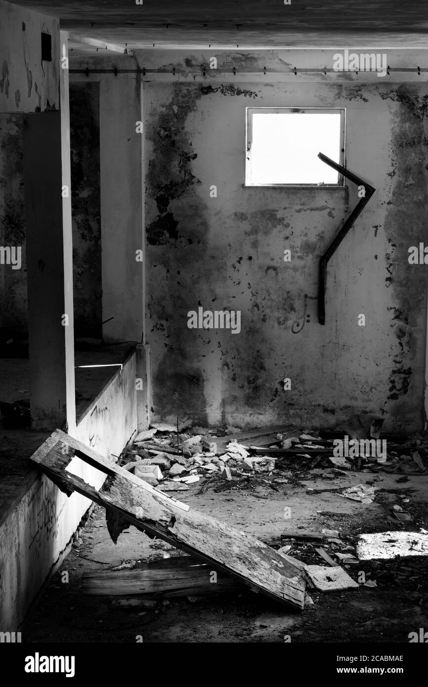 Black and white of looted room, destroyed door and window and rubble on the floor. Abandoned building located on Monte Grappa (Veneto, Italy) Stock Photo