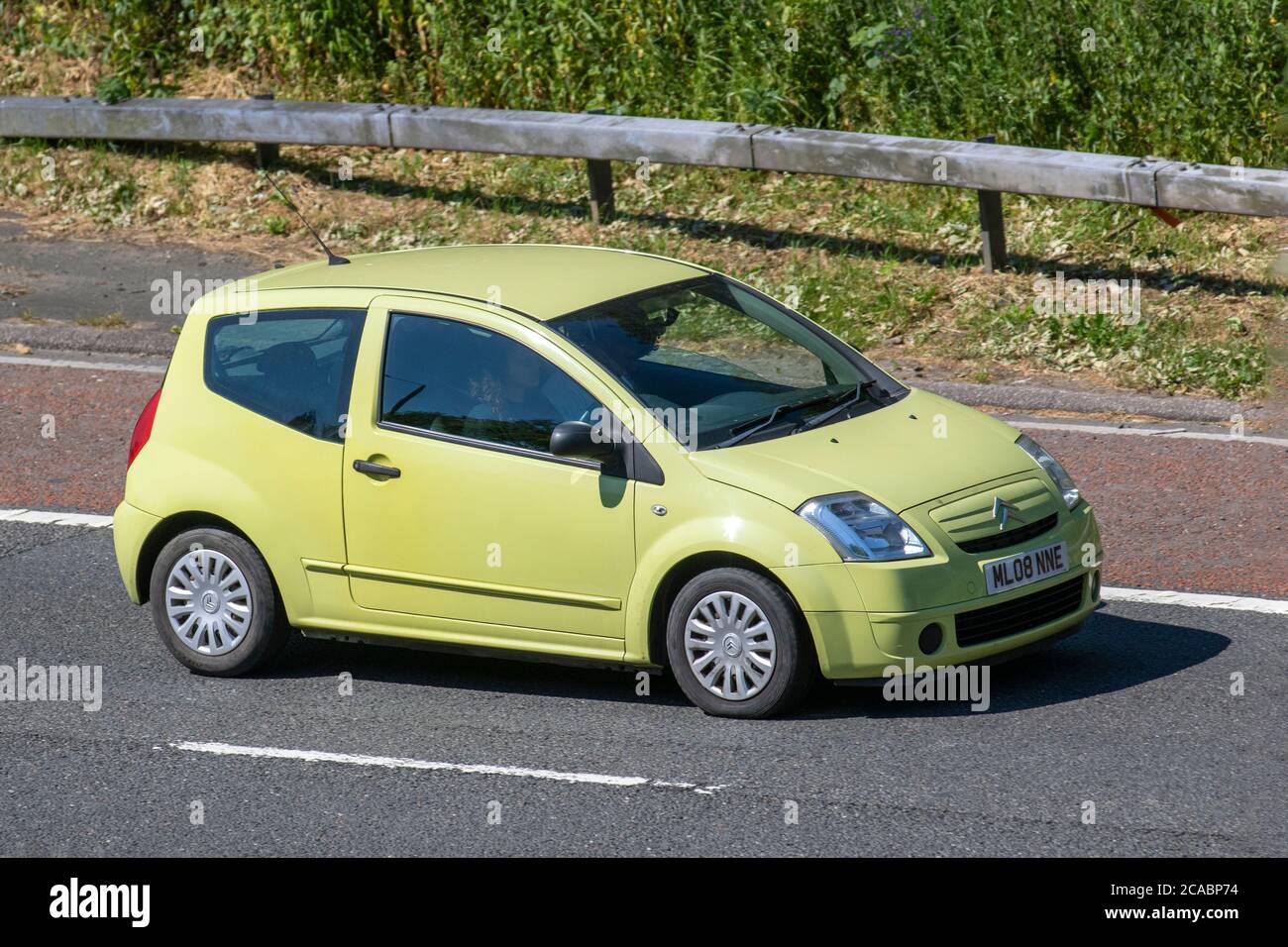 2008 yellow Citroën C2 Cool 2dr small city car; Vehicular traffic moving vehicles, cars driving vehicle on UK roads, motors, motoring on the M6 motorway highway network. Stock Photo