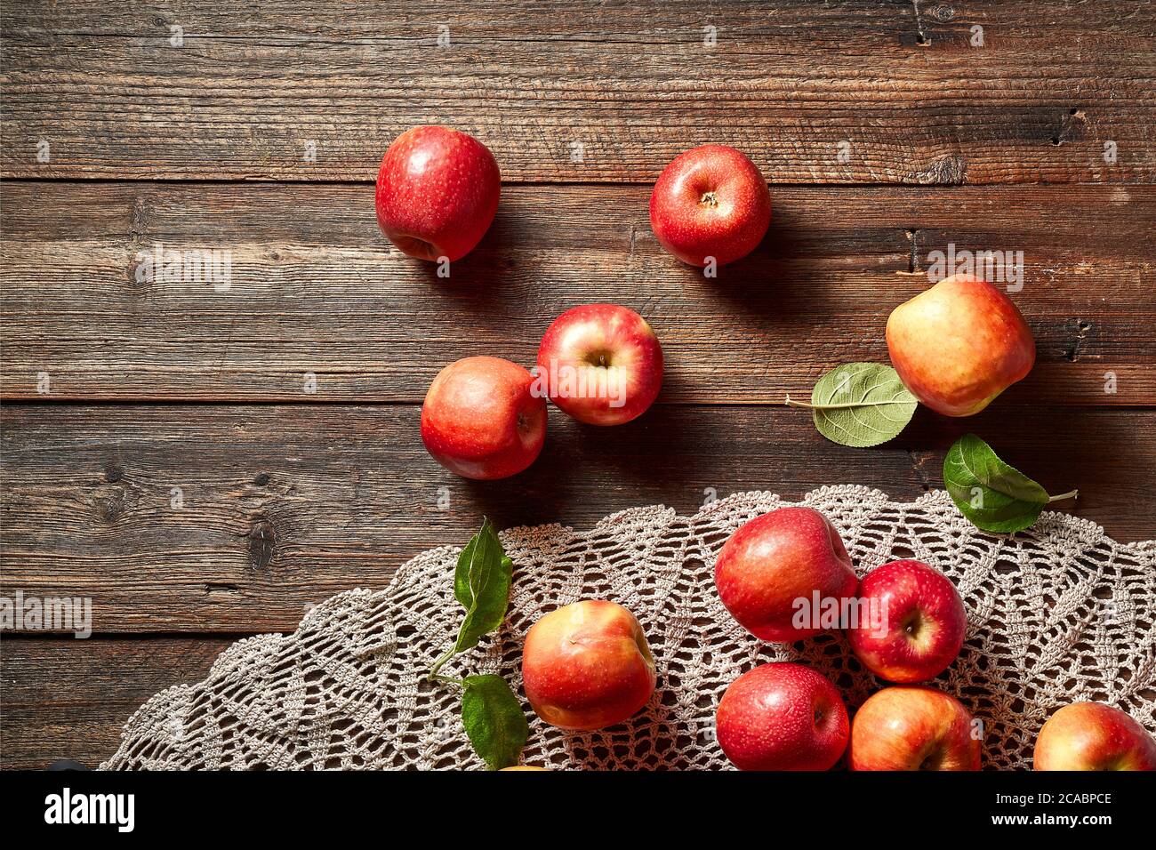 Red apple on rustic wooden table and crochet tablecloth. Summer or autumn season. Stock Photo