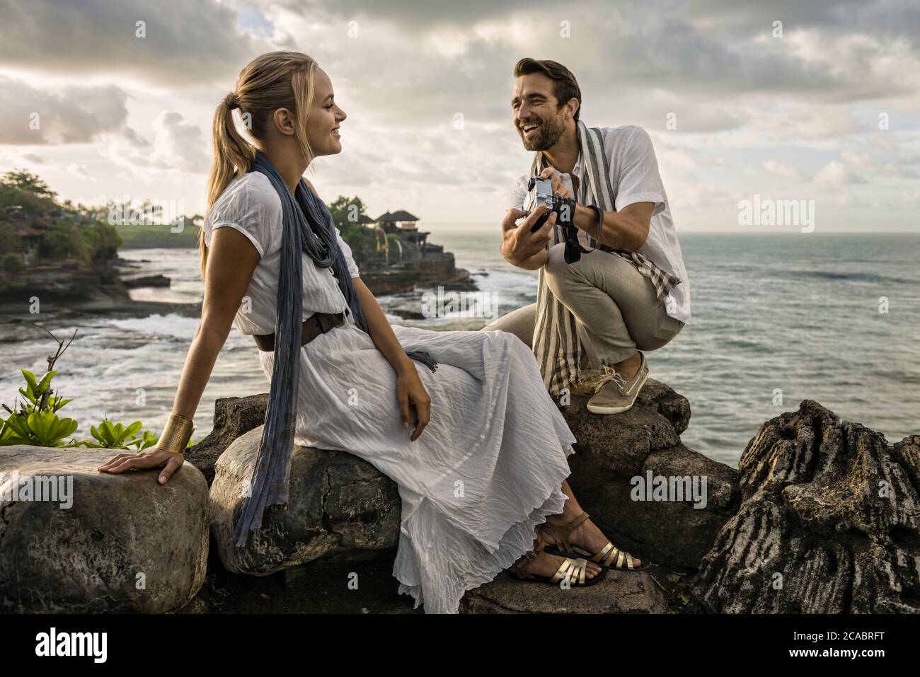 Asia, Indonesia, Bali, young Caucasian couple, wearing smart casual clothing, enjoying a visit to the famous Hindu temple Tanalot, which is one of the Stock Photo