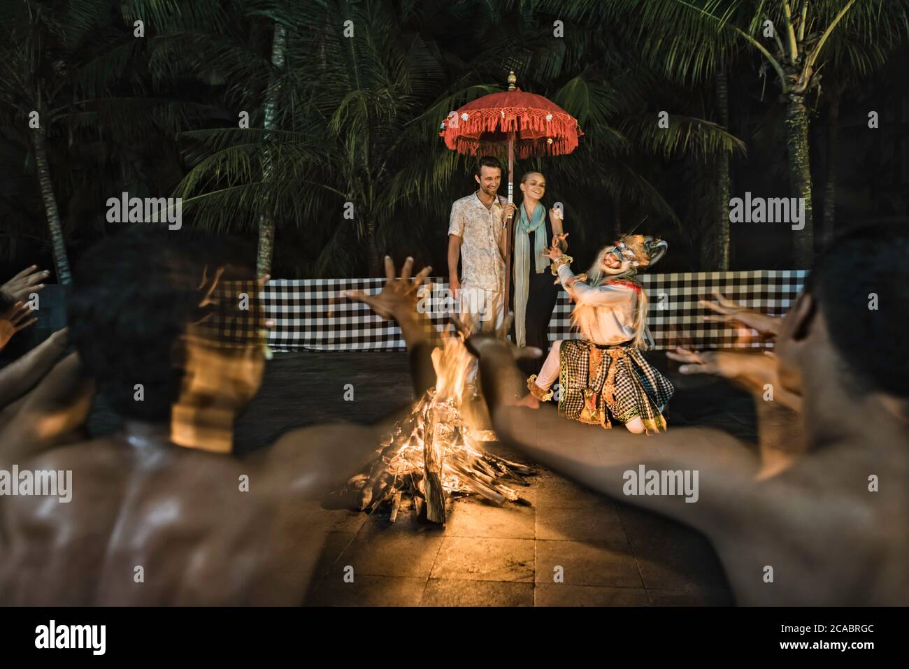 Asia, Indonesia, Bali, young Caucasian couple, wearing smart casual clothing, enjoying a traditional Balinese Kecak dance performed around a fire, at Stock Photo
