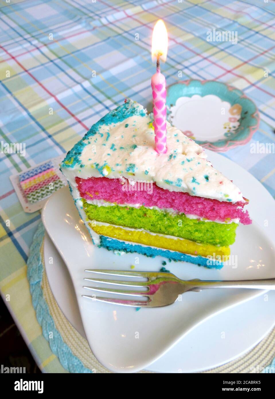 A slice of cake with white frosting and a candle Stock Photo