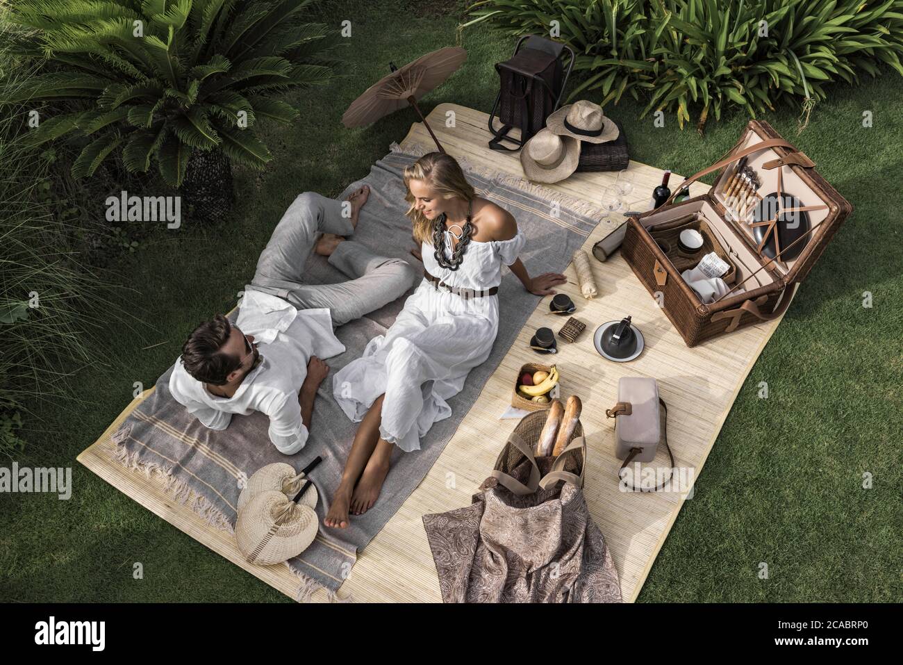 Asia, Indonesia, Bali, young Caucasian couple enjoying a luxury, authentic picnic, set in a tropical garden, , wearing smart casual clothing, while on Stock Photo