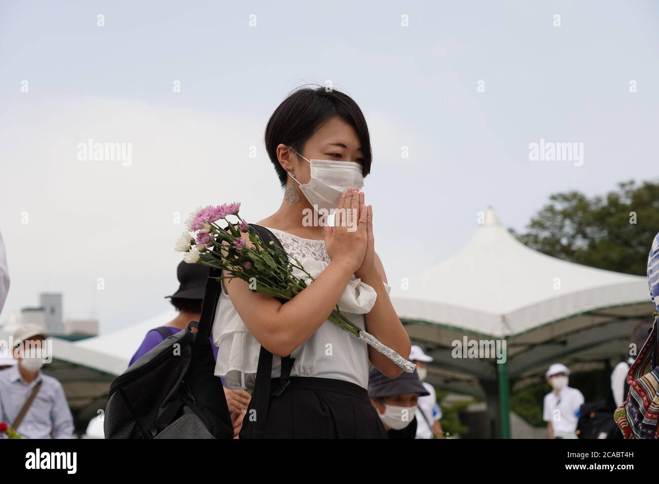 A woman prays while wearing a face mask at the Hiroshima Peace Memorial Ceremony.Hiroshima marks the 75th anniversary of the U.S. atomic bombing which killed about 150,000 people and destroyed the entire city during World War II. Stock Photo