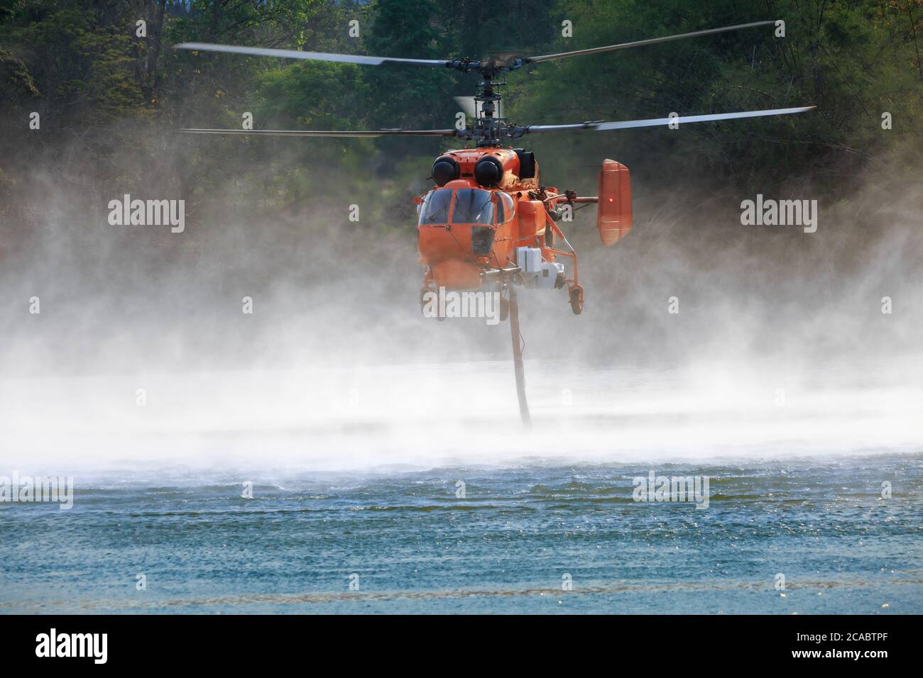 Firefighting helicopter is hovering over the pond to refills water Stock Photo Alamy
