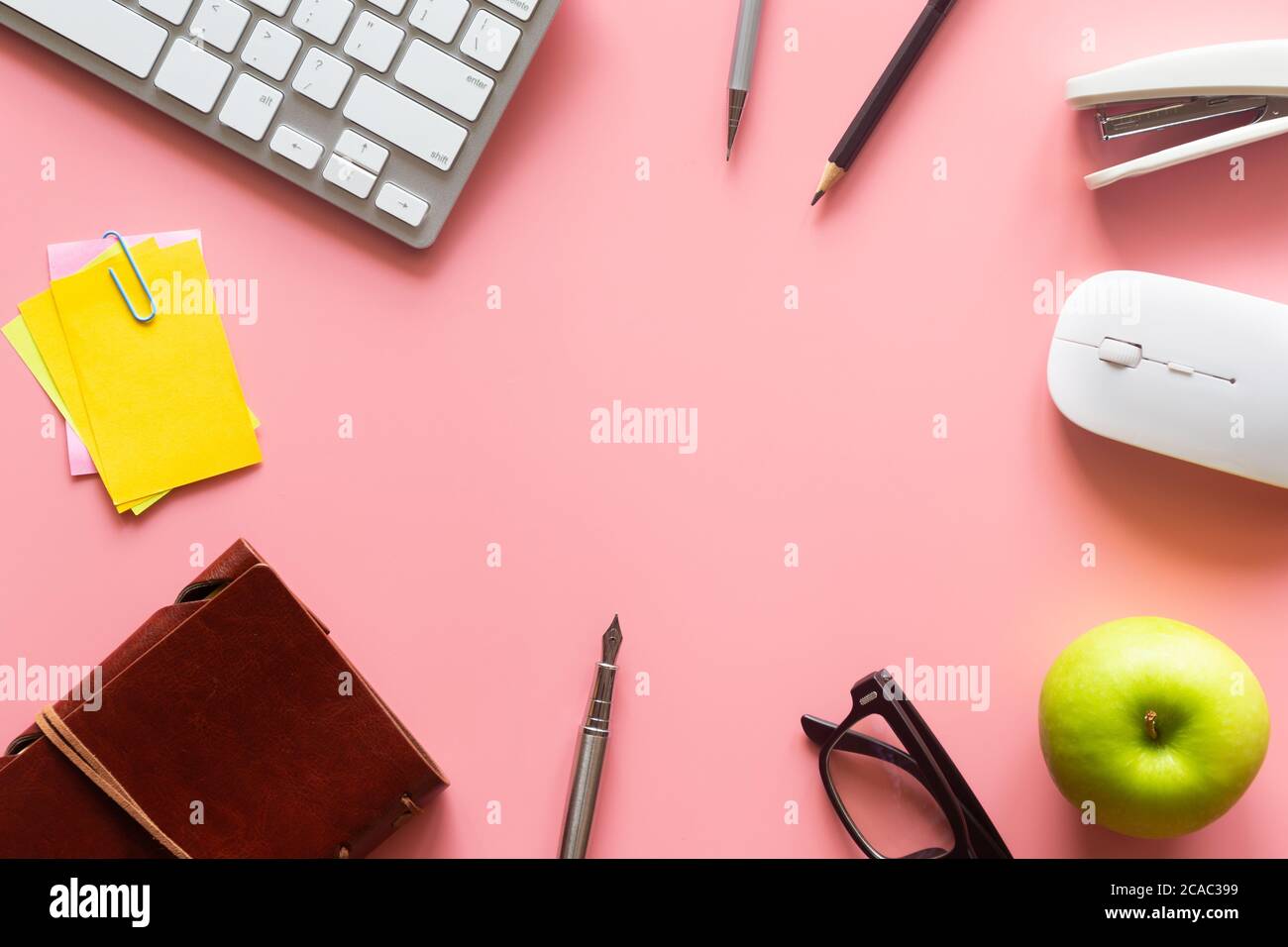 Pastel pink desk office with laptop, smartphone and other work supplies