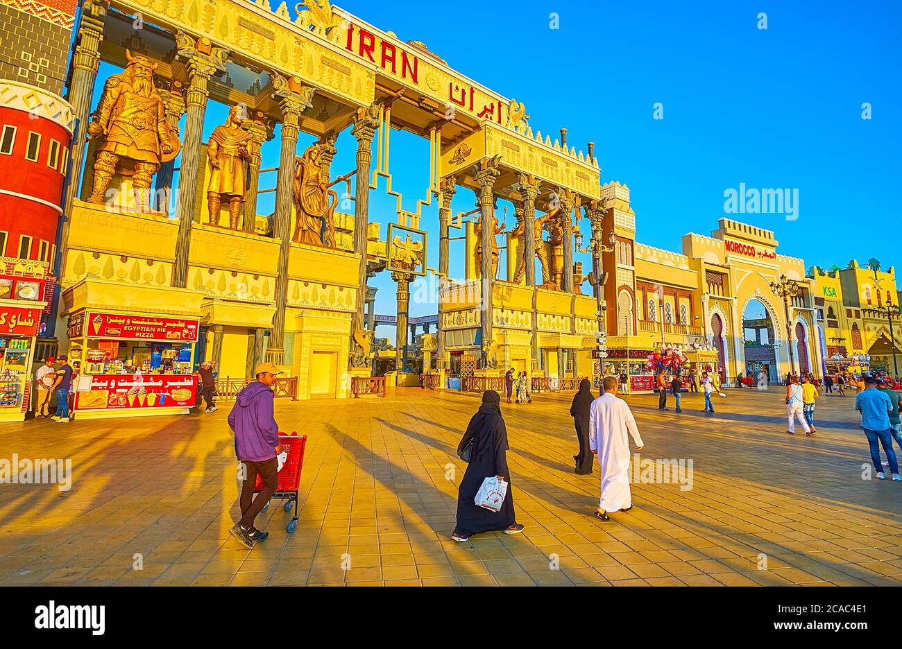 DUBAI, UAE - MARCH 5, 2020: The promenade of Global Village Dubai with pavilion of Iran, decorated with large sculptures, columns and reliefs in Persi Stock Photo