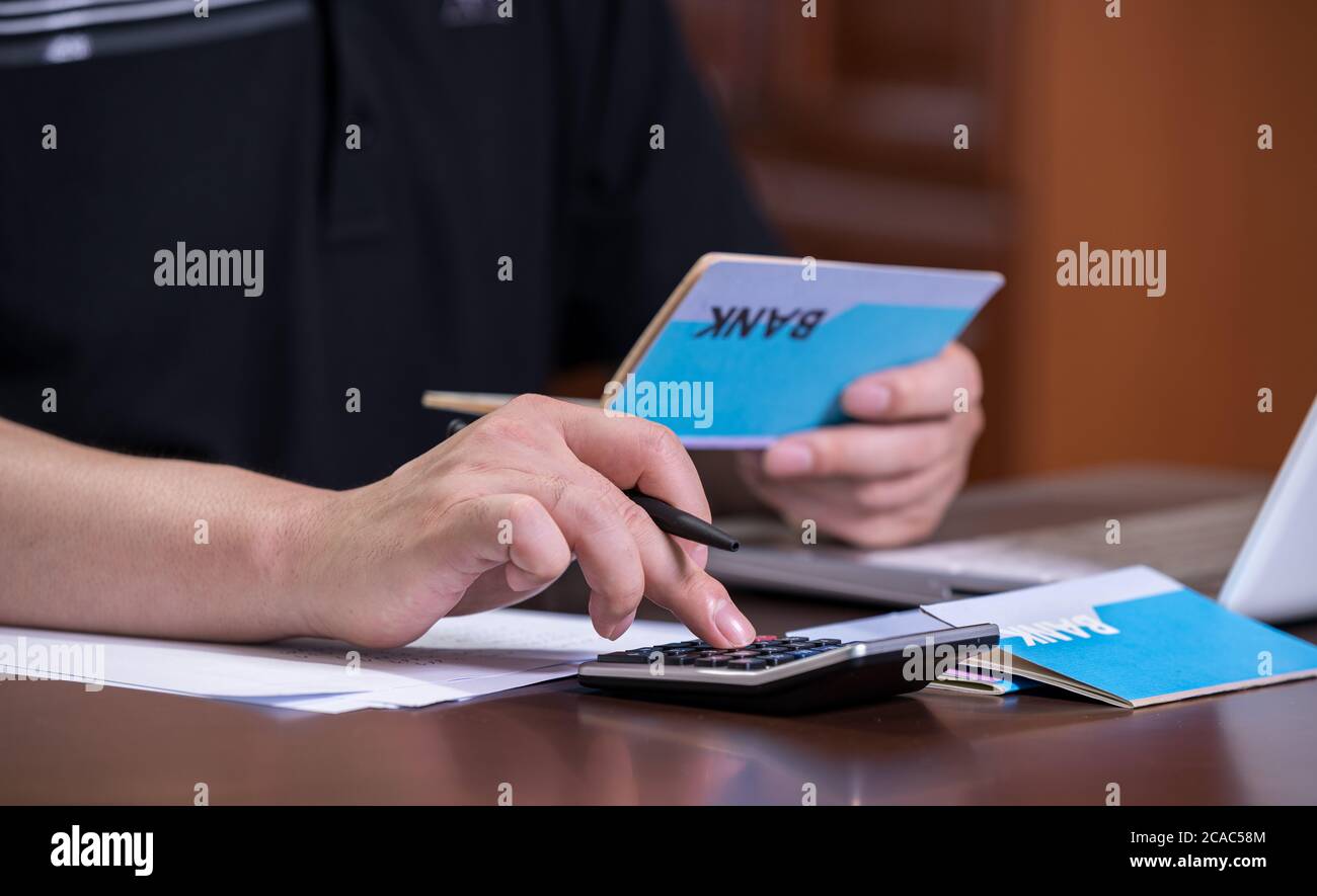 The hands of the men who are holding a bank passbook and weaving a budget. Stock Photo