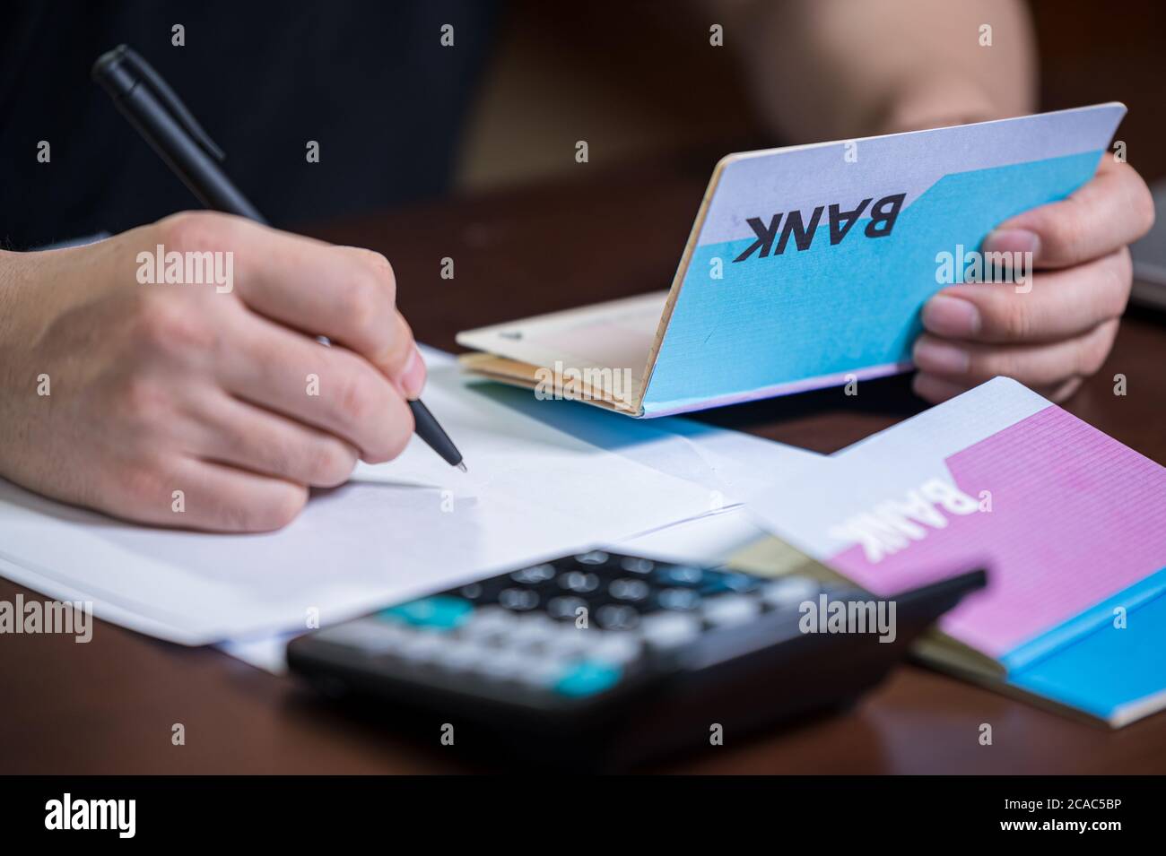 The hands of the men who are holding a bank passbook and weaving a budget. Stock Photo