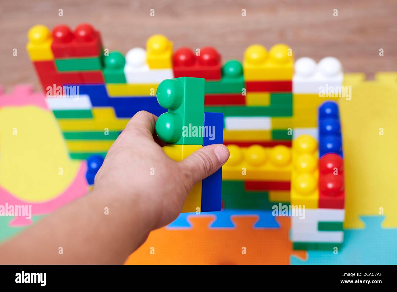 Hands of dad constructing wall with a colorful constructor set at home ...